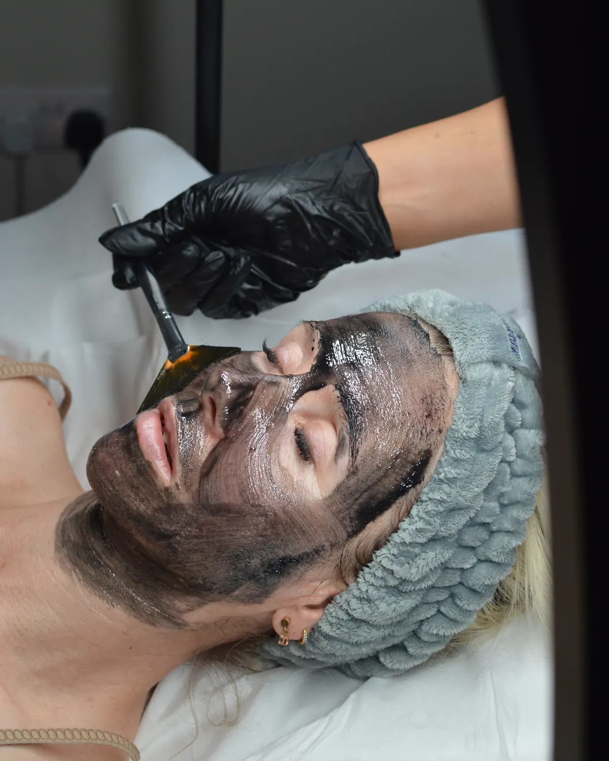 A clarifying charcoal mask being brushed on